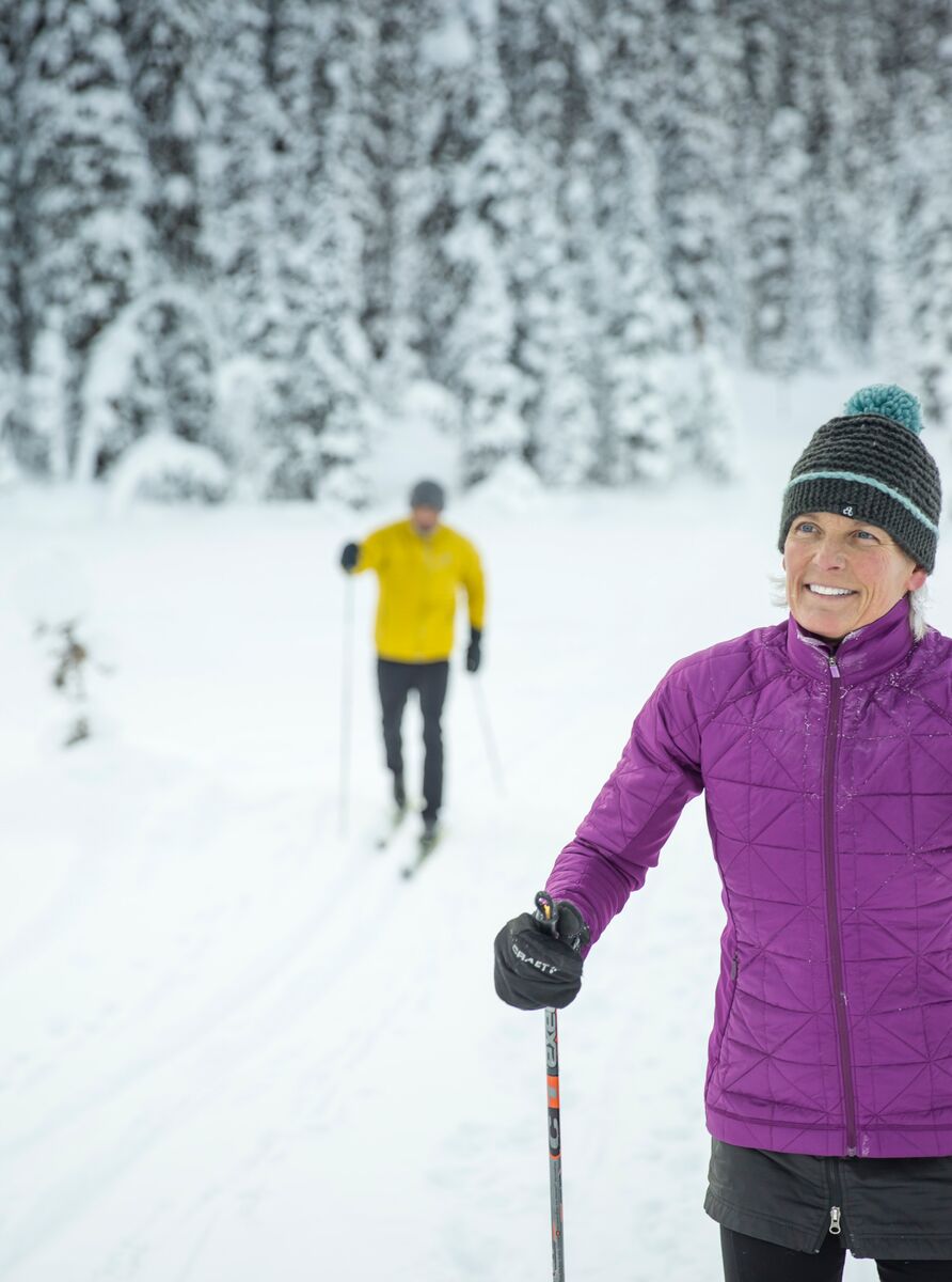 Two cross country skiers in a snowy forest in Banff National Park.